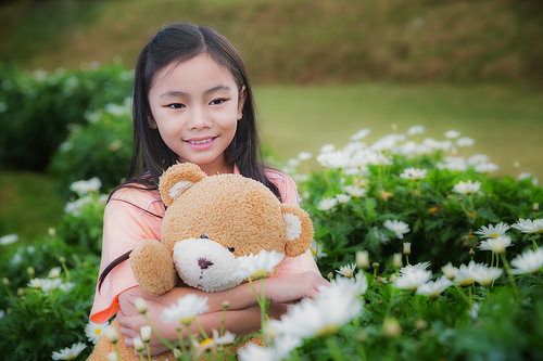 little girl with doll bear in nature park